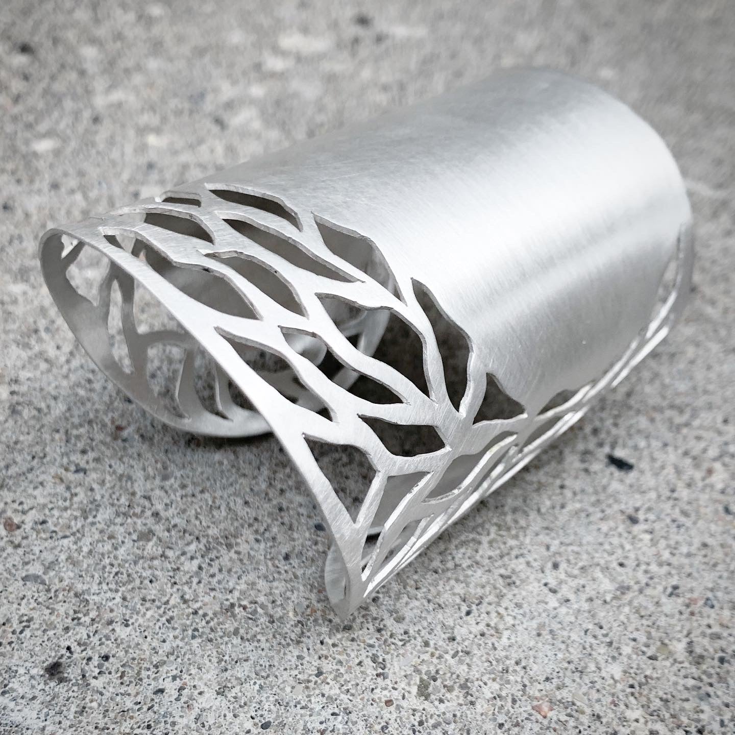Silver bracelet with intricate design on a concrete surface