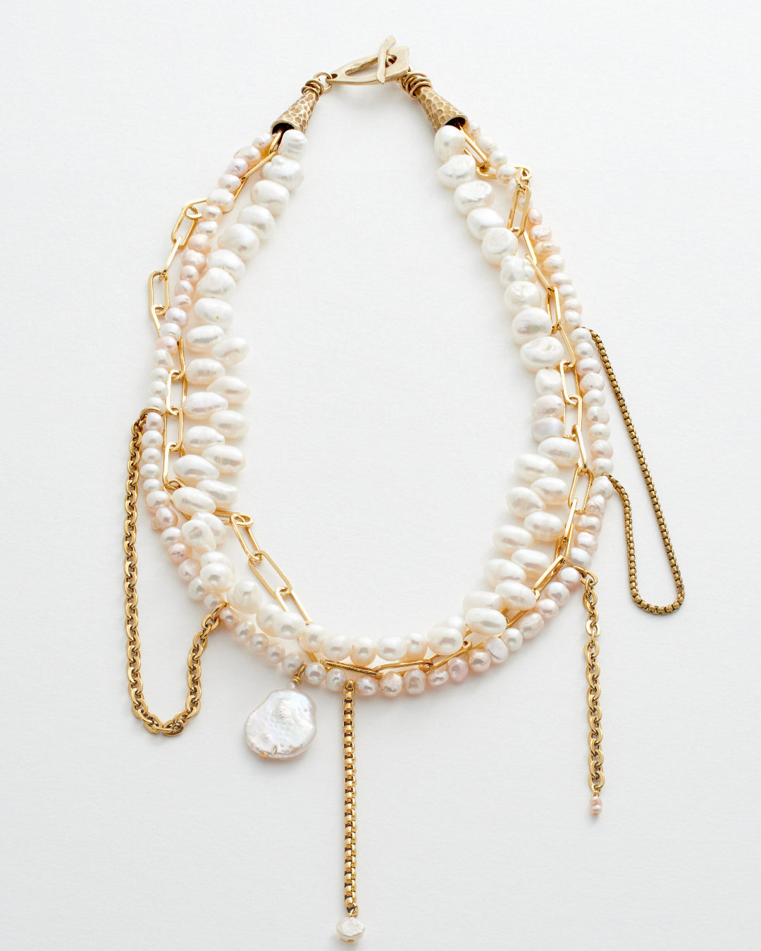 Multi-layered pearl and gold chain necklace on a white background