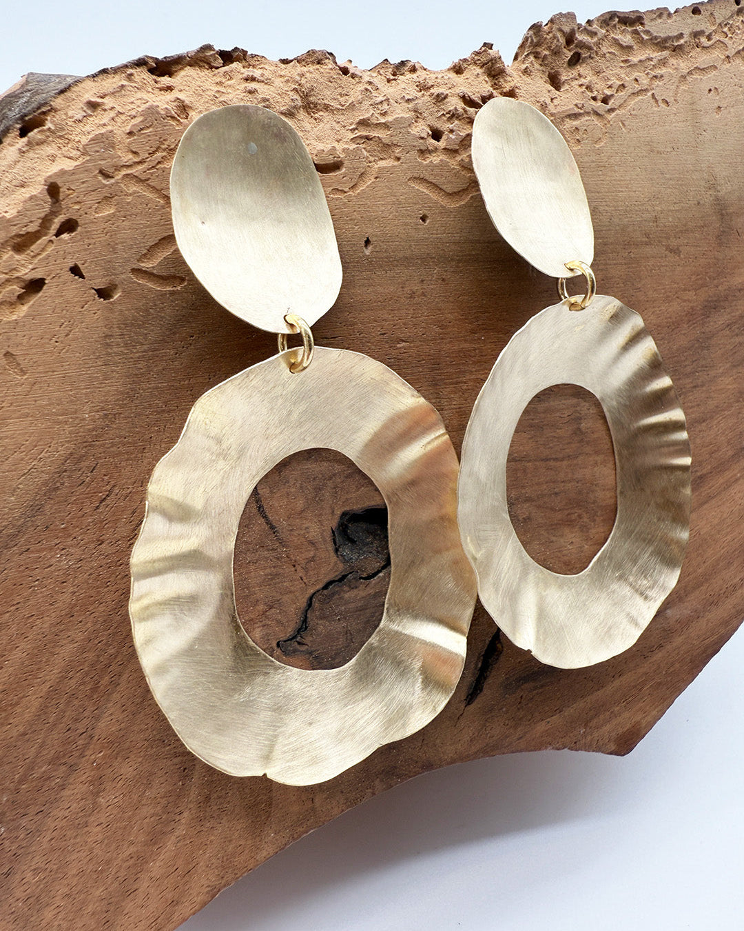 Gold earrings on a wooden surface