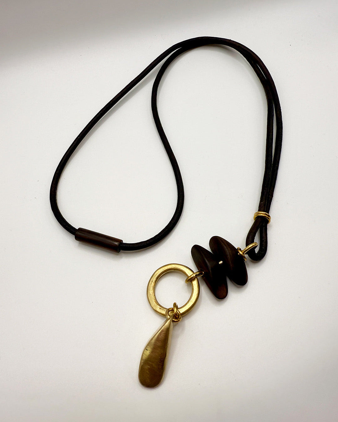 Necklace with gold pendant and dark beads on a white background