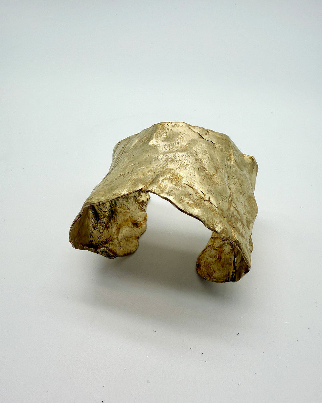 Gold ring with a natural, unpolished texture on a white background