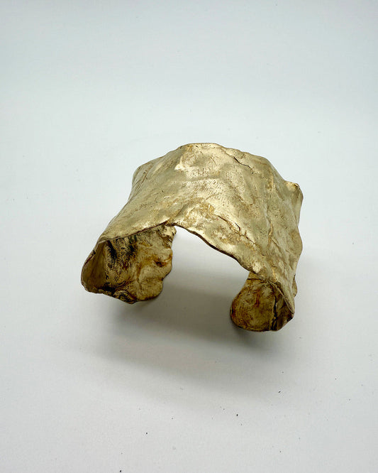 Gold ring with a natural, unpolished texture on a white background