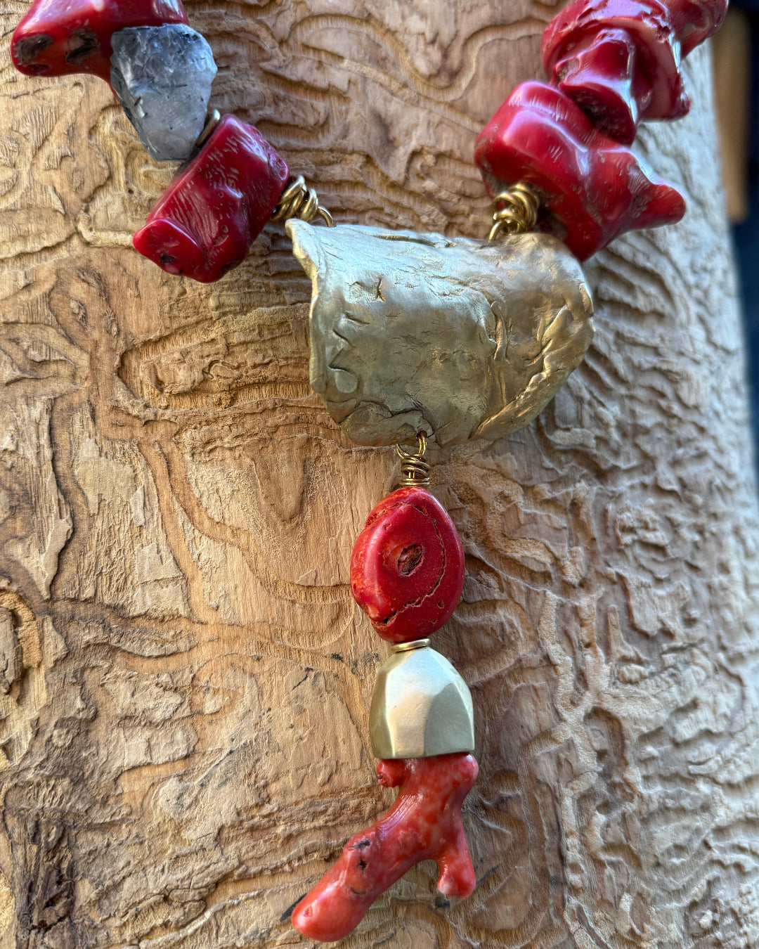 Close up of necklace with red and gold beads on a textured surface
