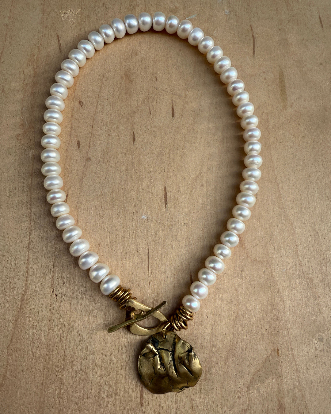 Pearl necklace with a gold clasp on a wooden surface