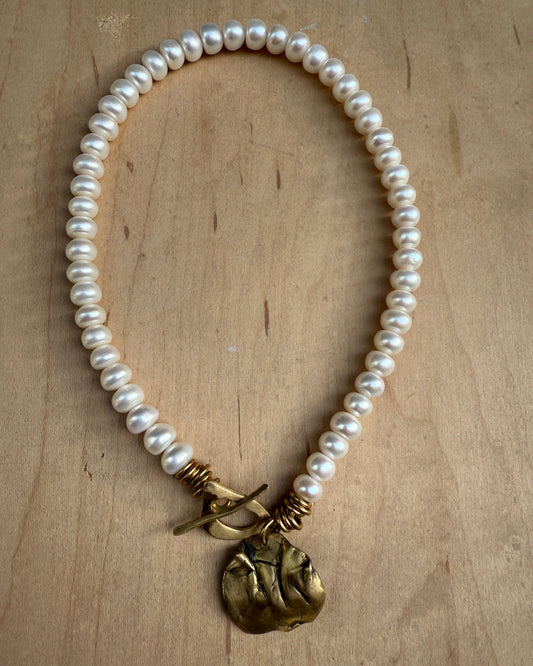 Pearl necklace with a gold clasp on a wooden surface