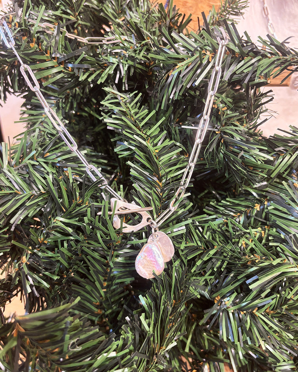 Necklace with a pearl pendant on a green leafy background