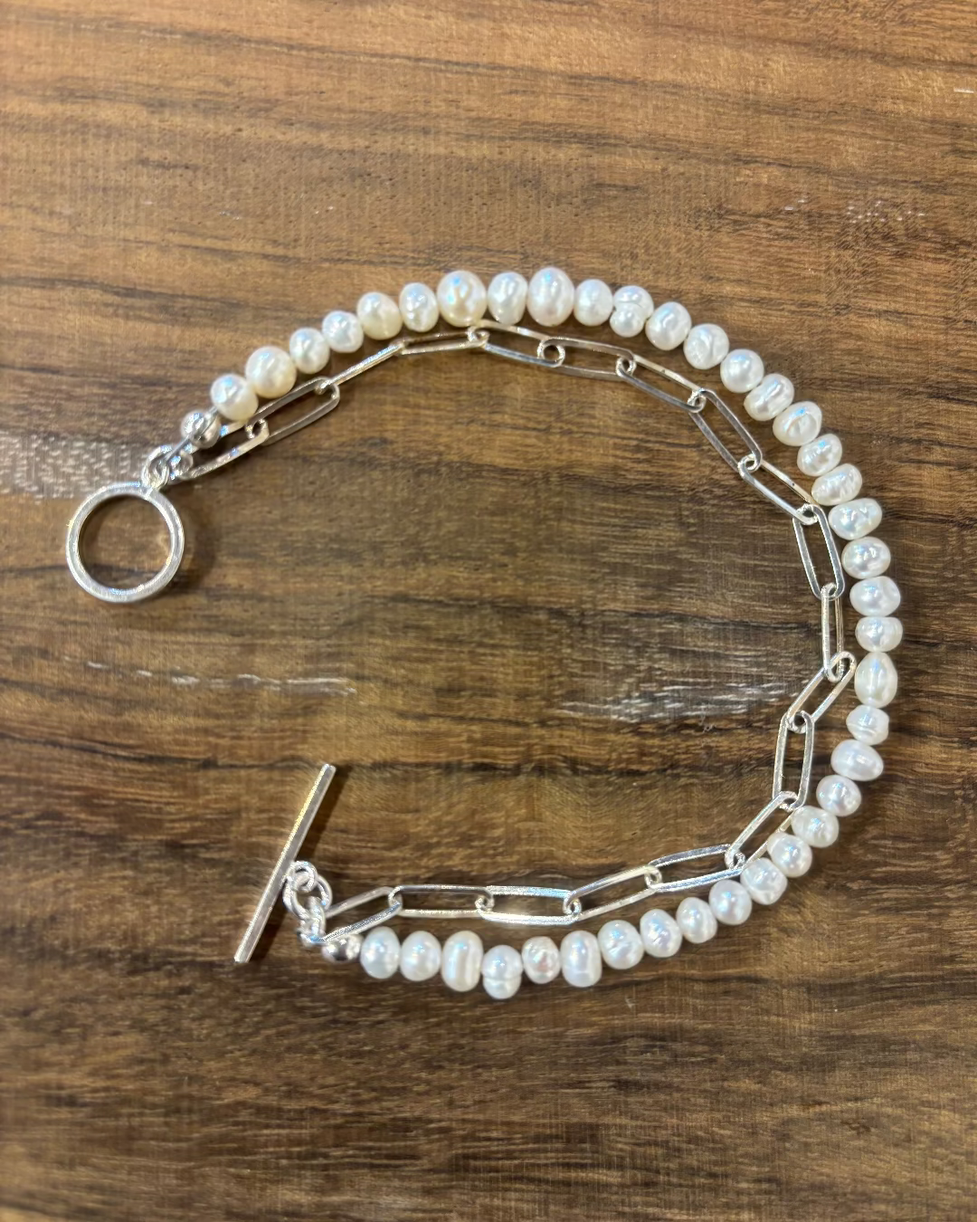 Pearl bracelet with silver clasp on a wooden surface