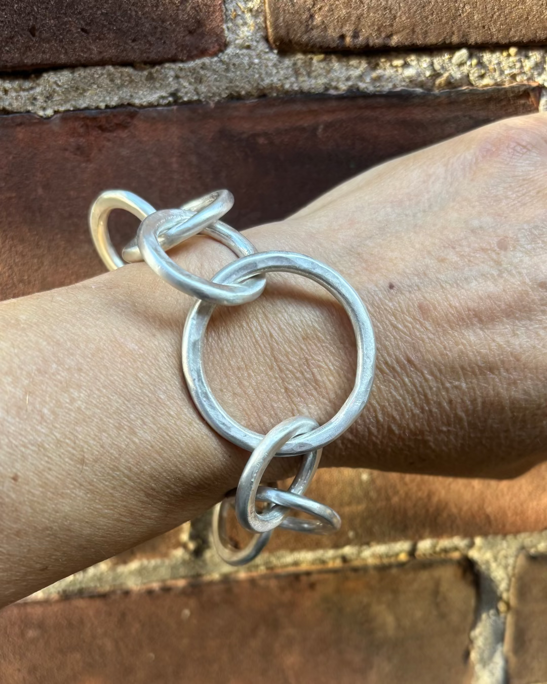 Silver bracelet on a wrist with a brick wall background