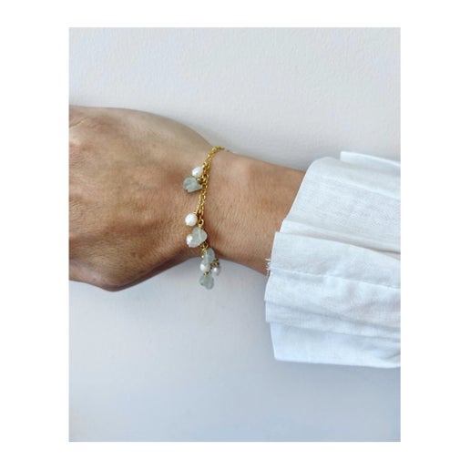 Bracelet with pearls and small stones on a wrist against a white background