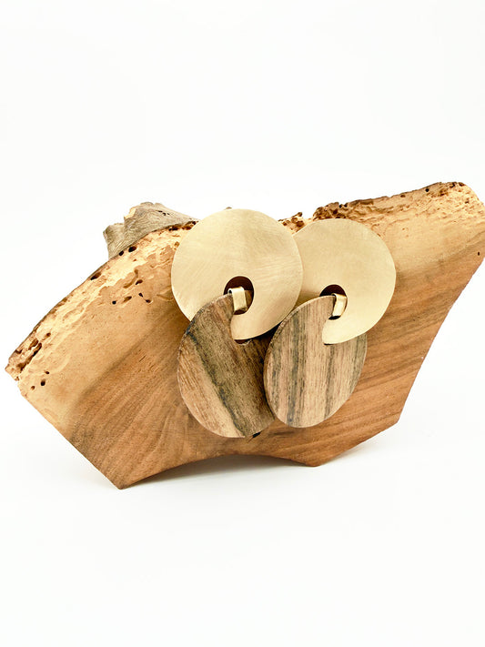 Pair of gold earrings on a wooden surface with a white background