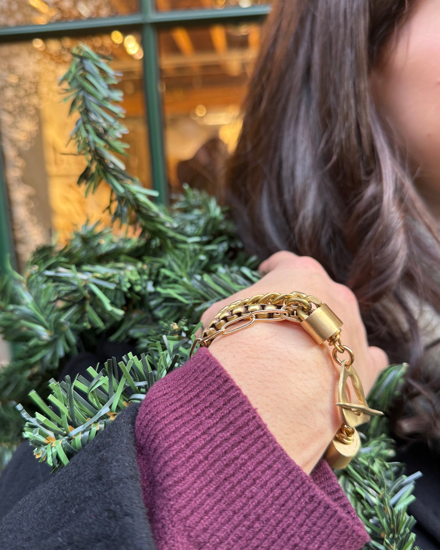 Close-up of a hand wearing a gold bracelet on a blurred festive background