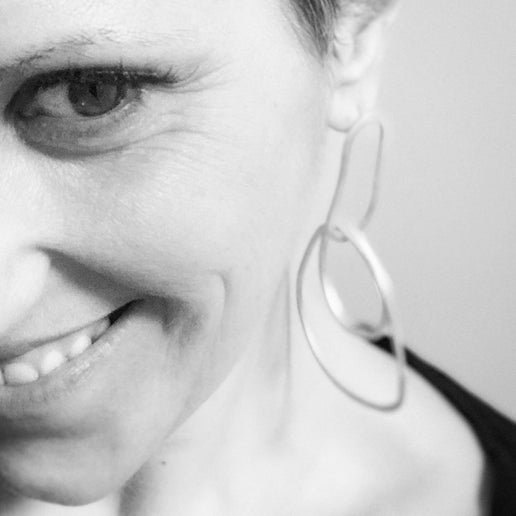 Close-up of a woman wearing hoop earrings with a neutral background