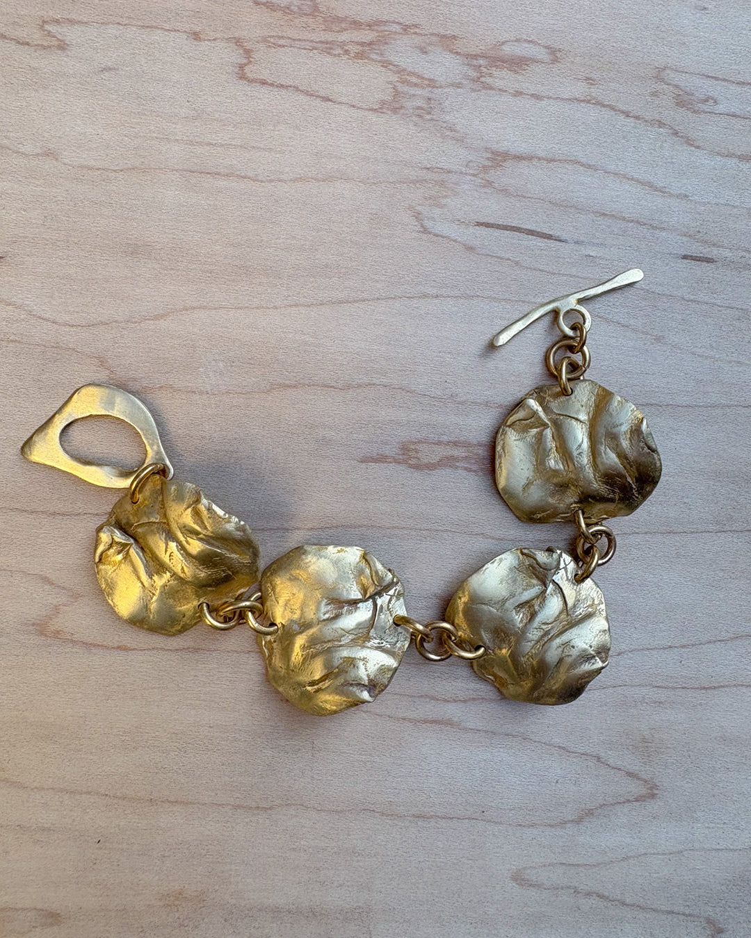 Bronze bracelet with coral-like pendants on a wooden surface