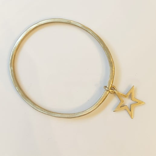 Gold bangle with a star charm on a light beige background