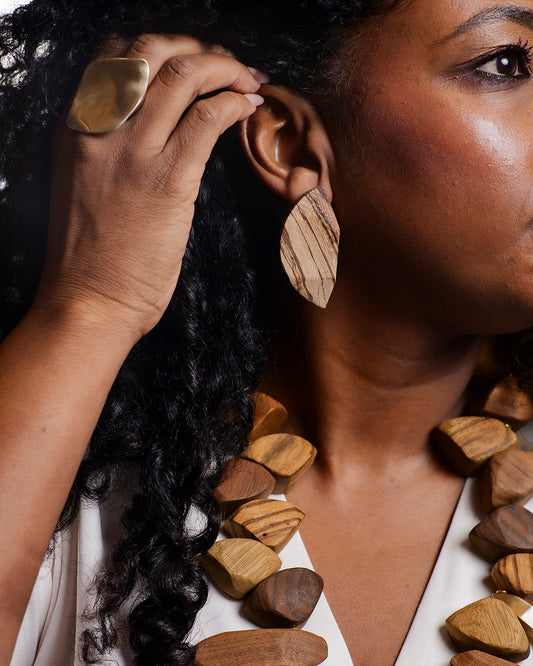 Person wearing large wooden earrings with a close-up of the earrings on a white background