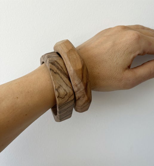 Two wooden bracelets on a wrist against a white background