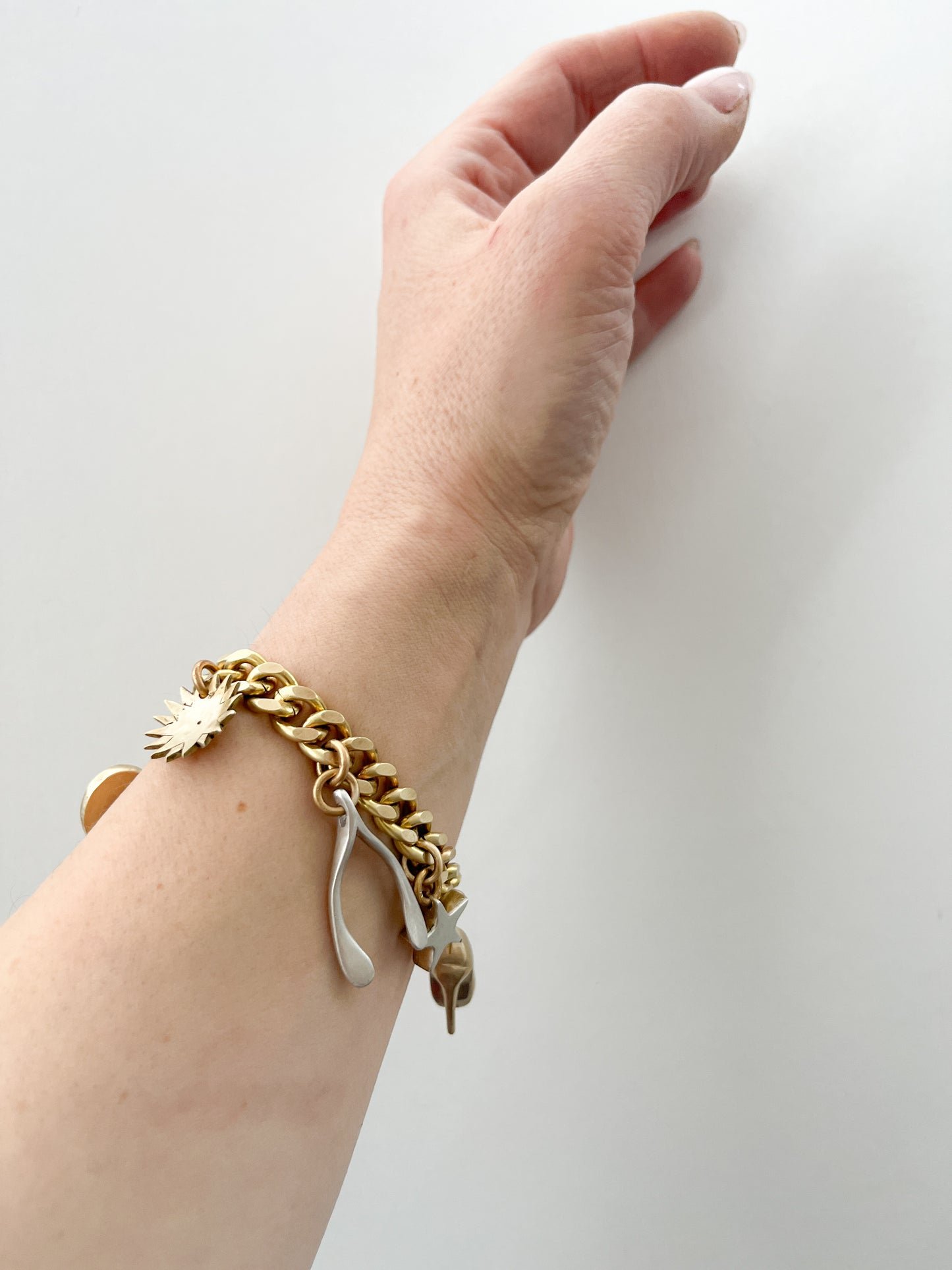 Gold bracelet with charms on a wrist against a white background