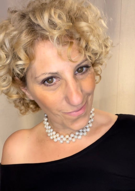 Woman wearing a pearl necklace against a neutral background