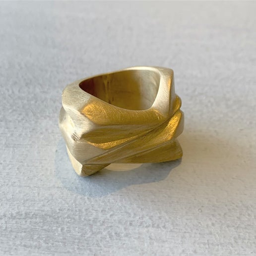Gold ring with a textured design on a light gray background