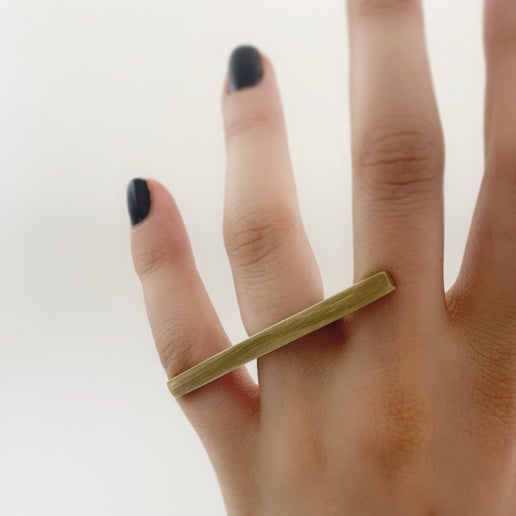 Gold ring on a finger with a plain background
