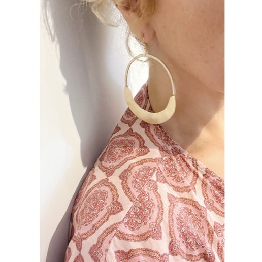 Close-up of a person wearing a large hoop earring with a patterned top.