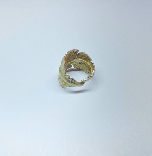 Bronze feather-shaped ring on a light grey background