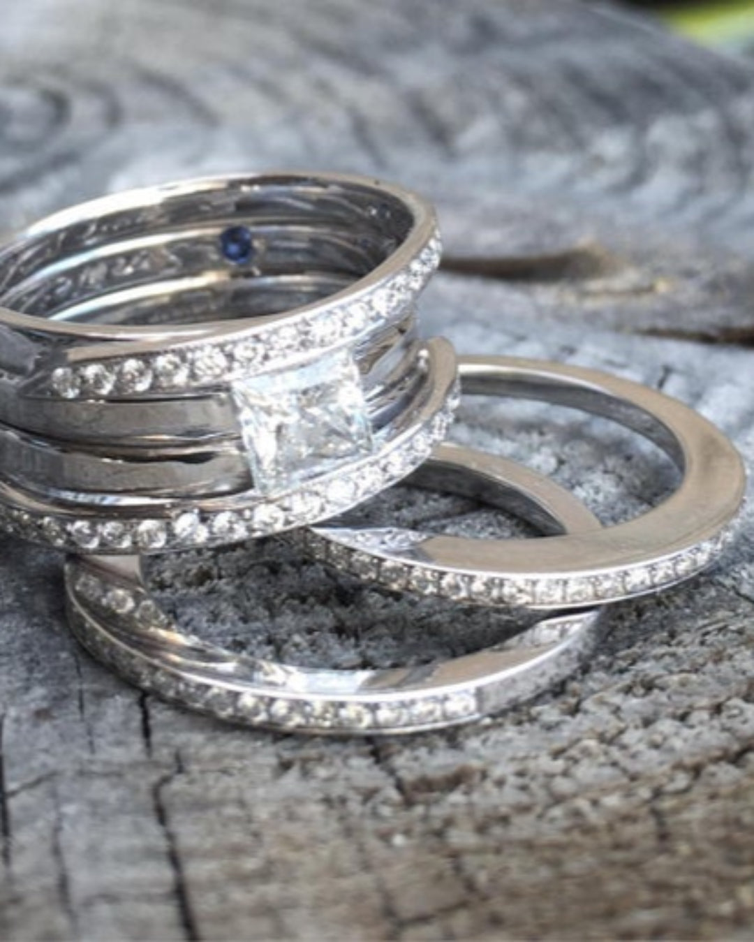 Stack of diamond rings. Two diamond bands and a ring featuring two diamond bands and one large diamond on a textured surface