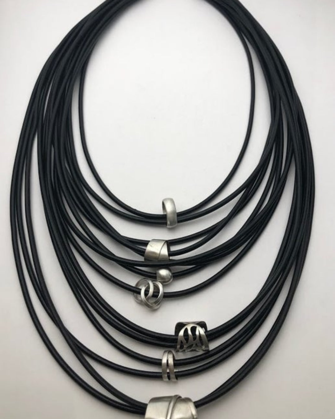 Multistrand black leather necklace with silver details on a light gray background