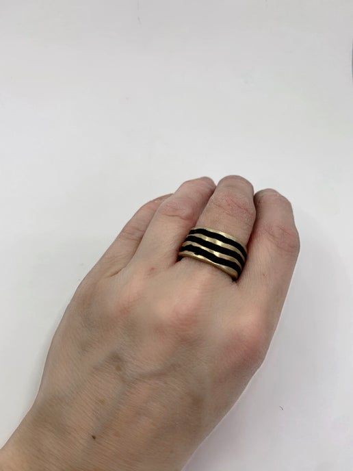 Hand wearing a textured gold ring on a white background