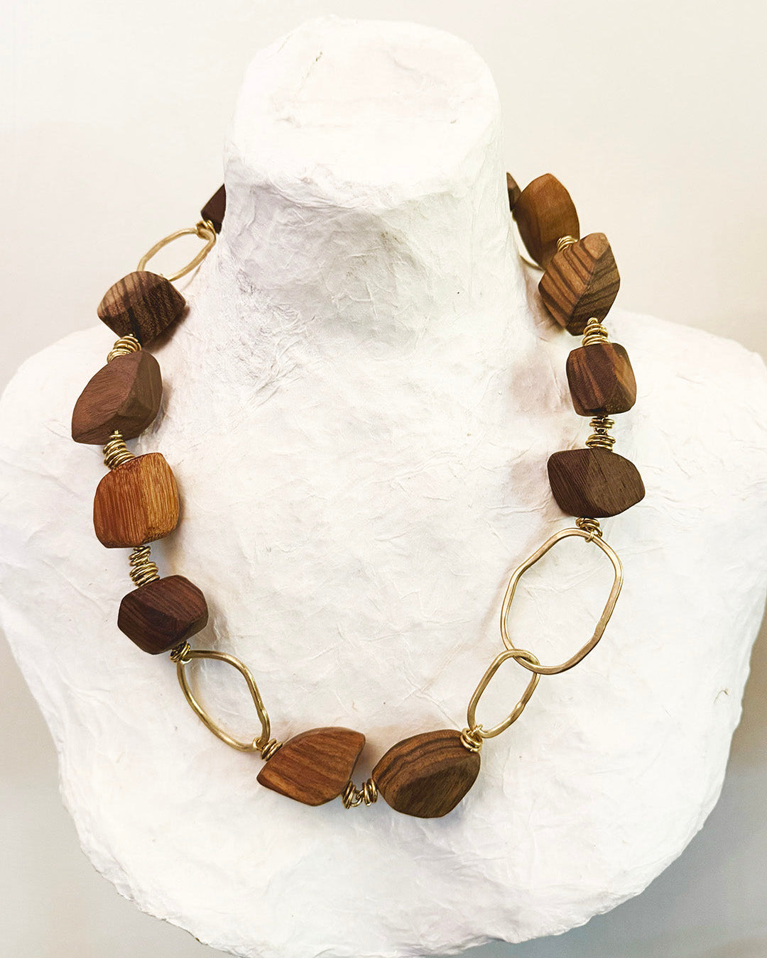 Necklace with wooden beads and gold links on a white stone surface