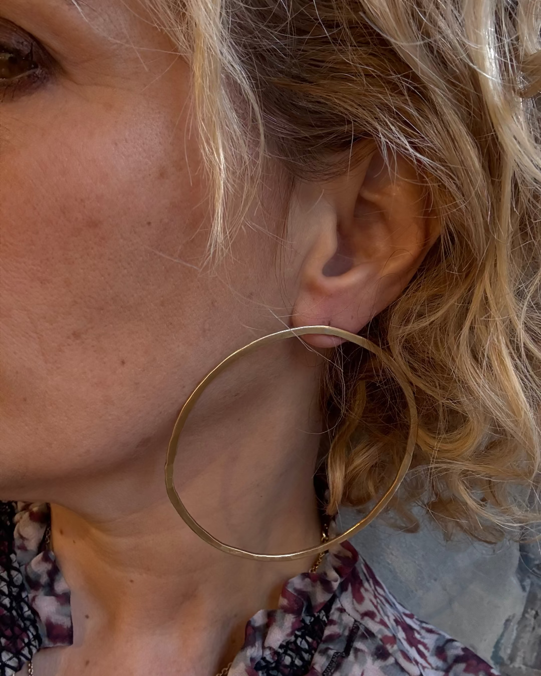 Close-up of a woman wearing a gold hoop earring with blurred background