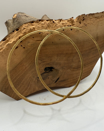 Two gold rings on a piece of wood with a white background