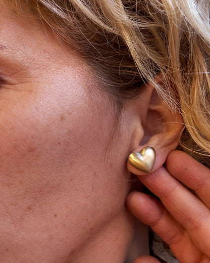 Close-up of a person wearing a gold heart-shaped earring.