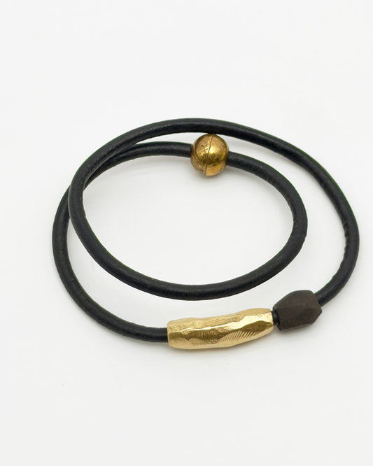 Black leather bracelet with gold accents on a white background