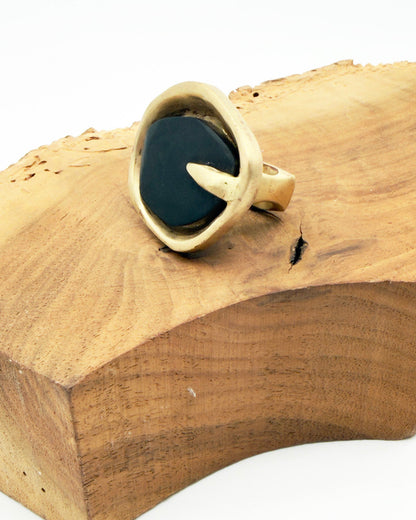 Gold ring with a dark stone on a wooden block