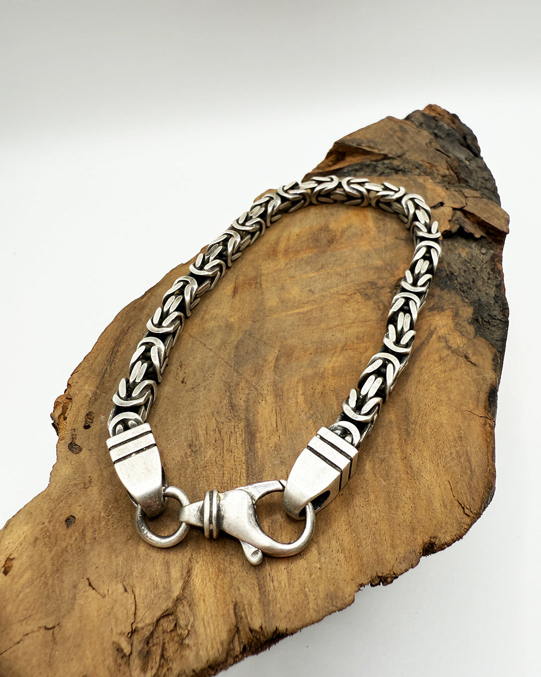 Silver bracelet with intricate design on a wooden surface