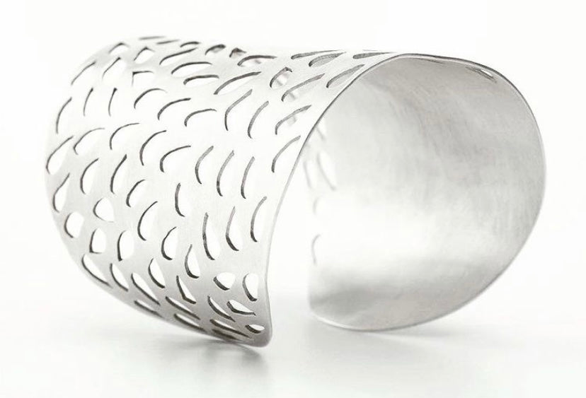 Silver bracelet with intricate design on a white background