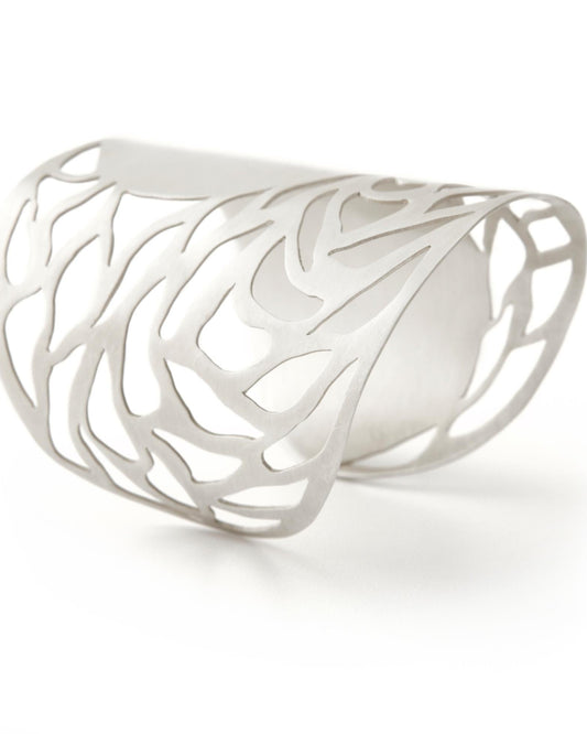 Silver cuff with intricate design on a white background