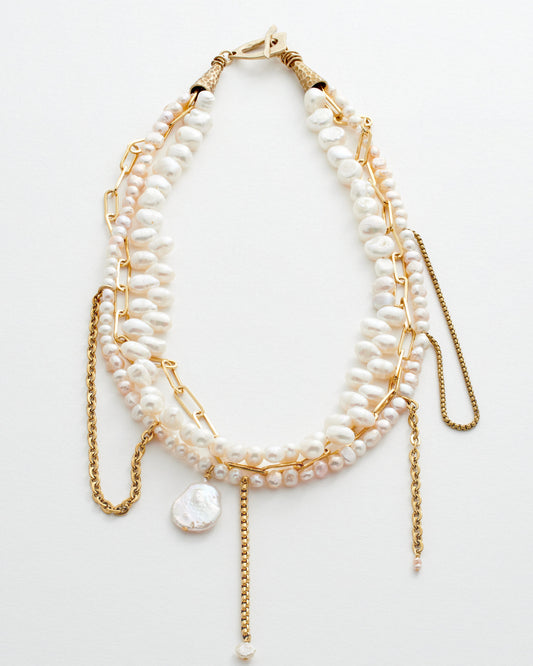 Multi-layered pearl and gold chain necklace on a white background
