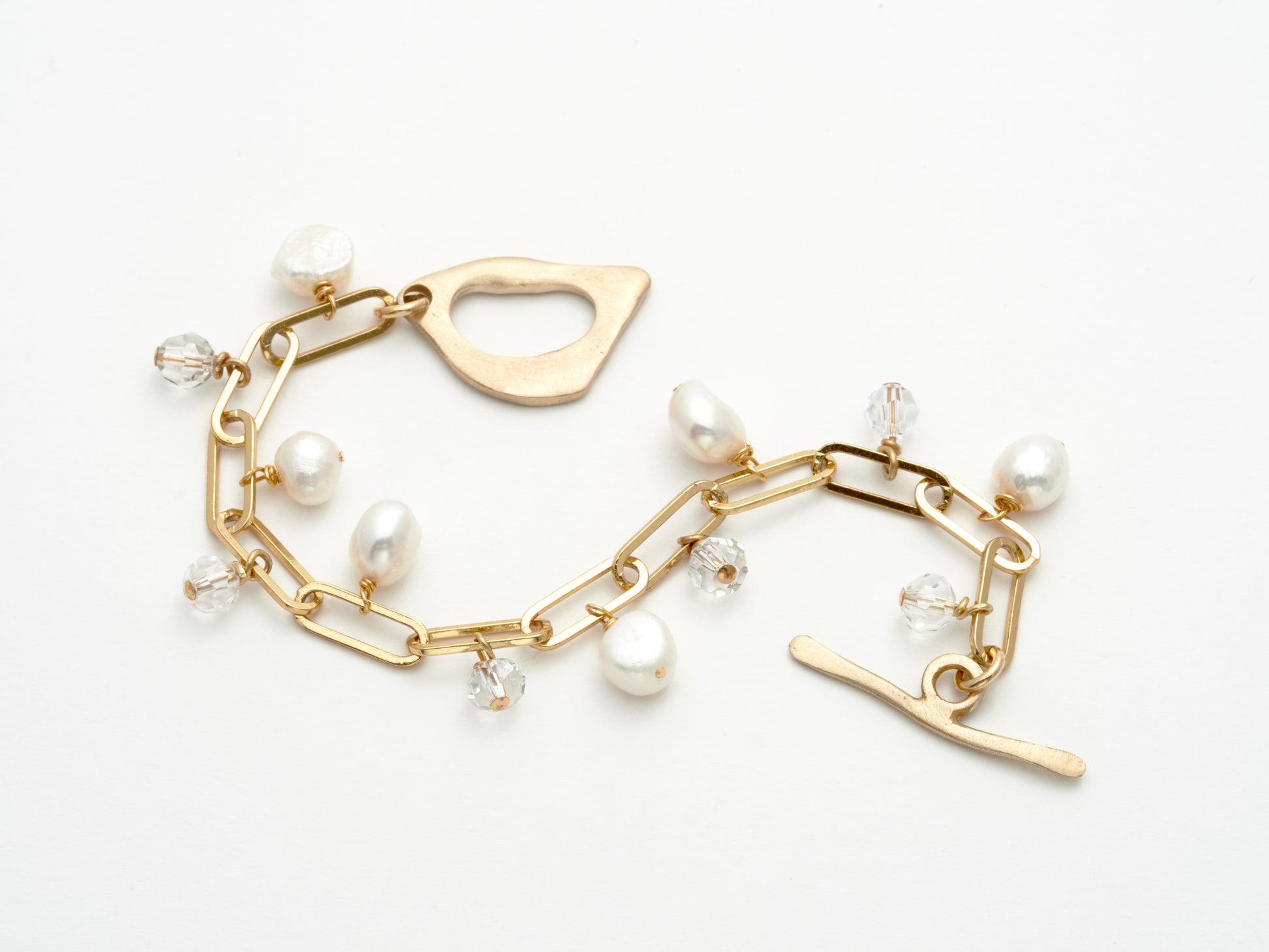 Gold bracelet with pearl charms on a white background