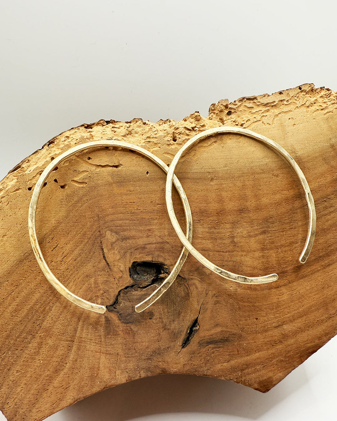 Gold hoop earrings on a wooden surface