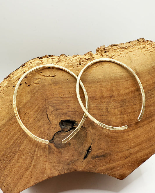 Gold hoop earrings on a wooden surface