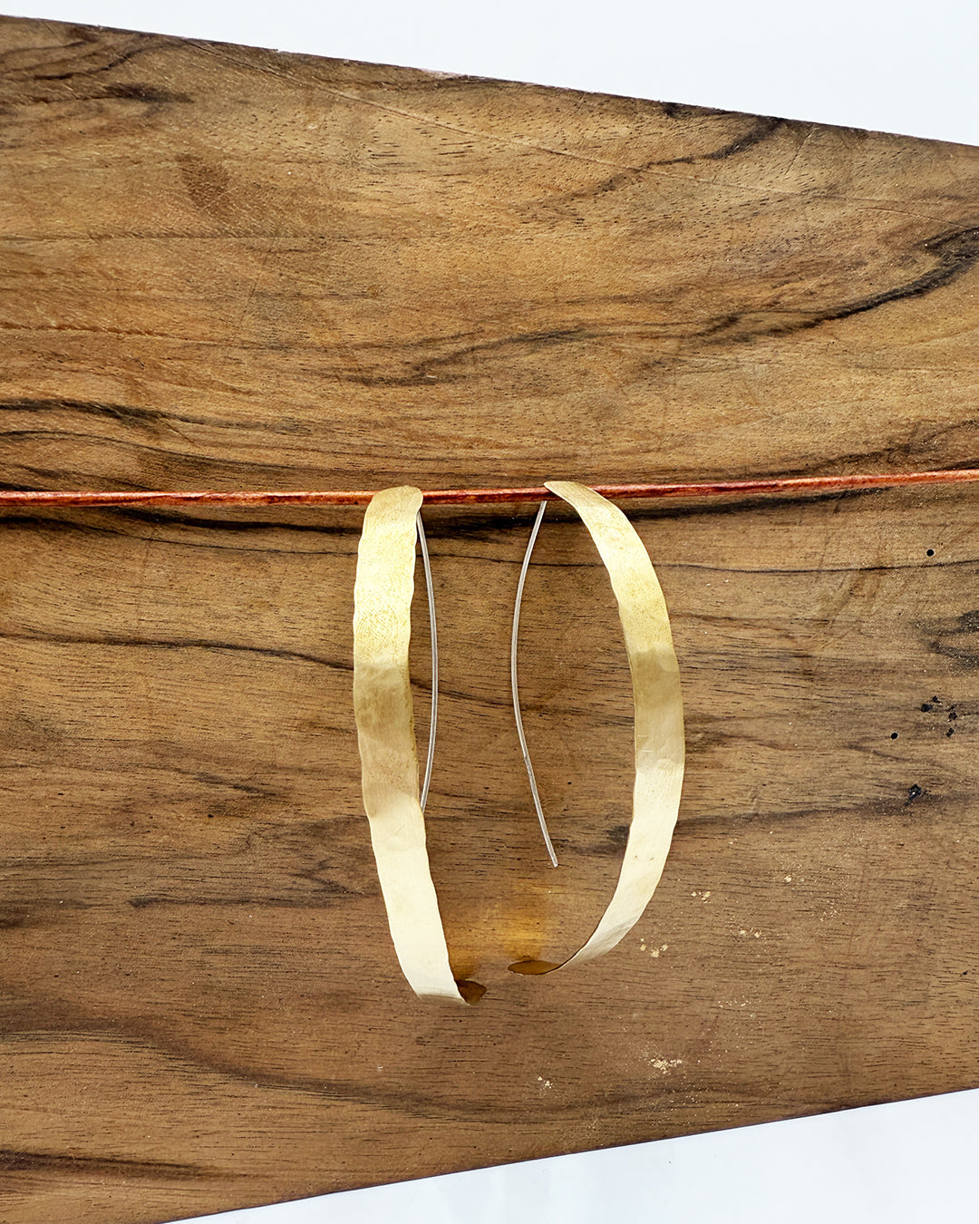Gold hoop earrings on a wooden surface