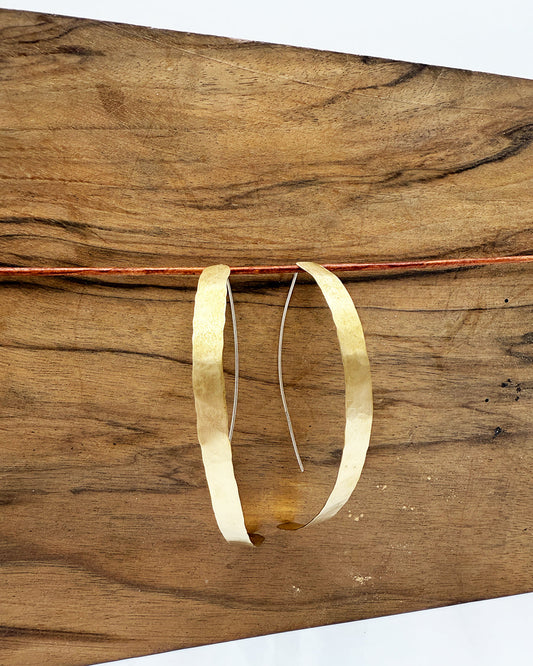 Gold hoop earrings on a wooden surface
