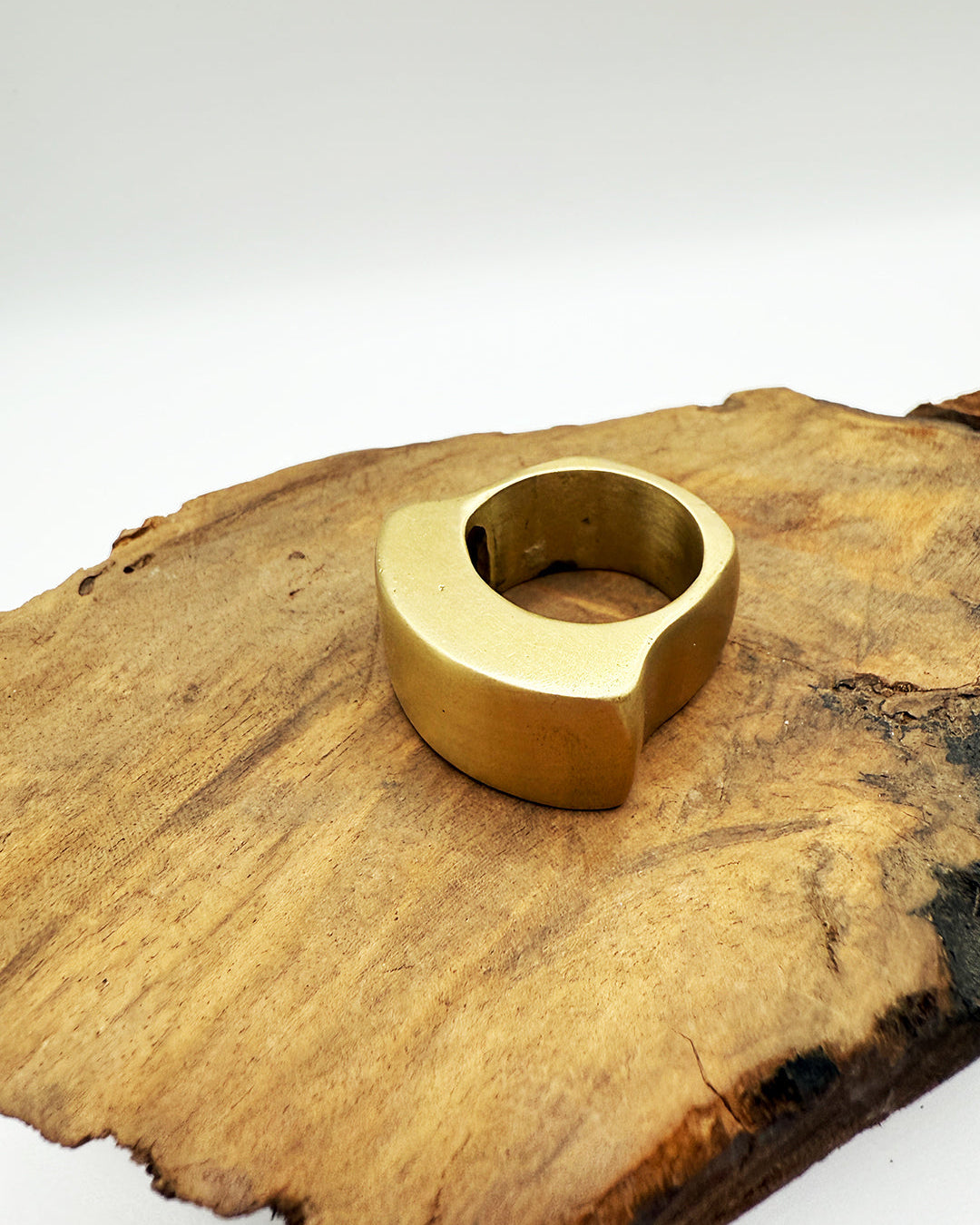Gold ring on a wooden surface with a white background