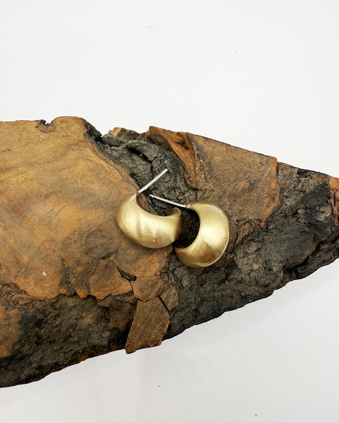 Gold hoop earrings on a piece of brown stone