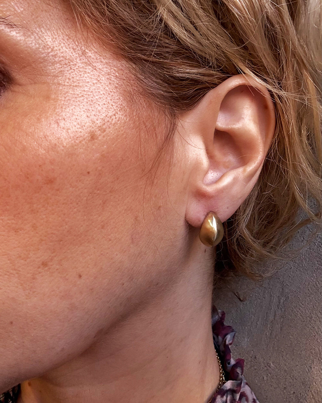 Close-up of a person wearing a gold earring.