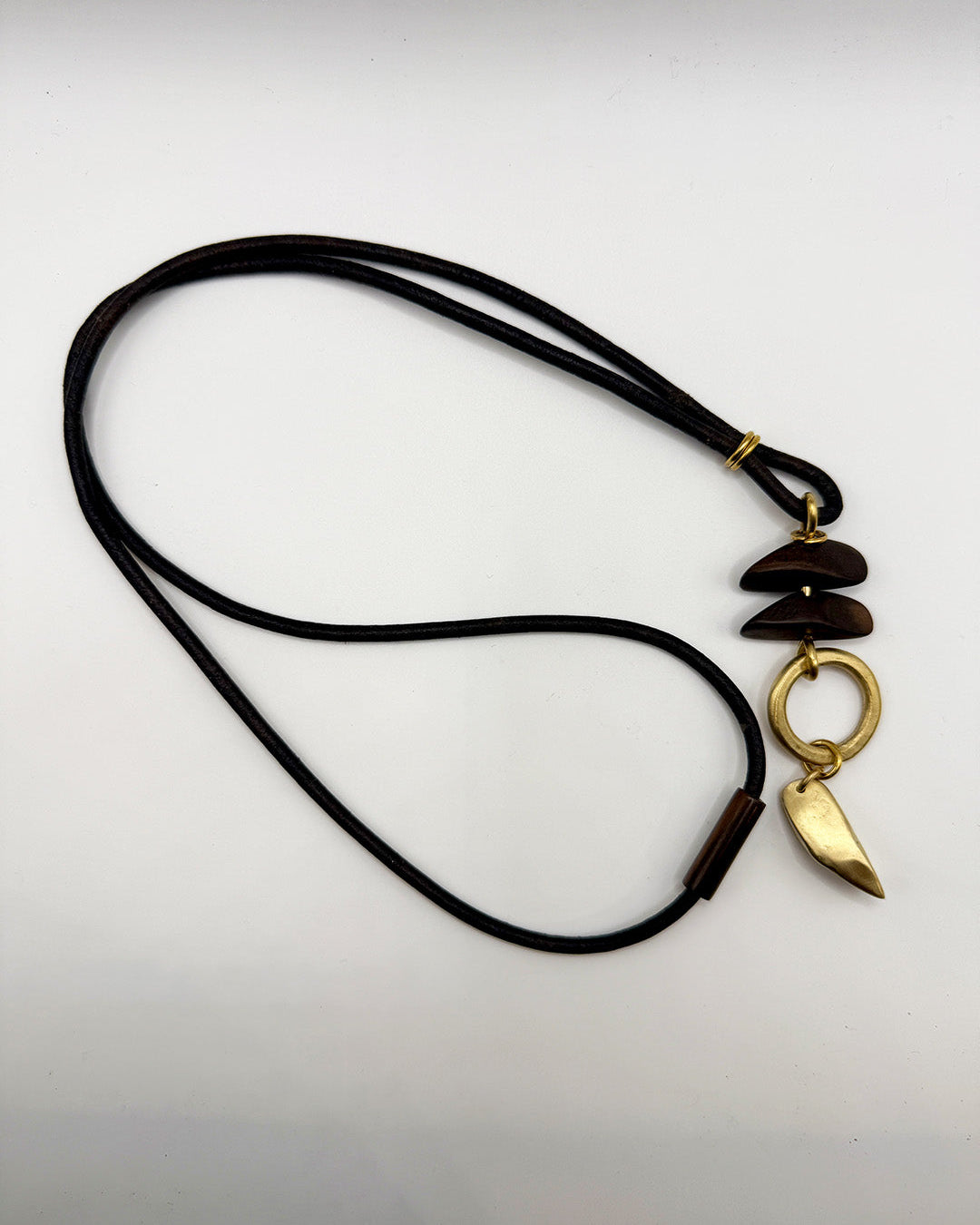 Necklace with black cord and gold pendant on a light gray background
