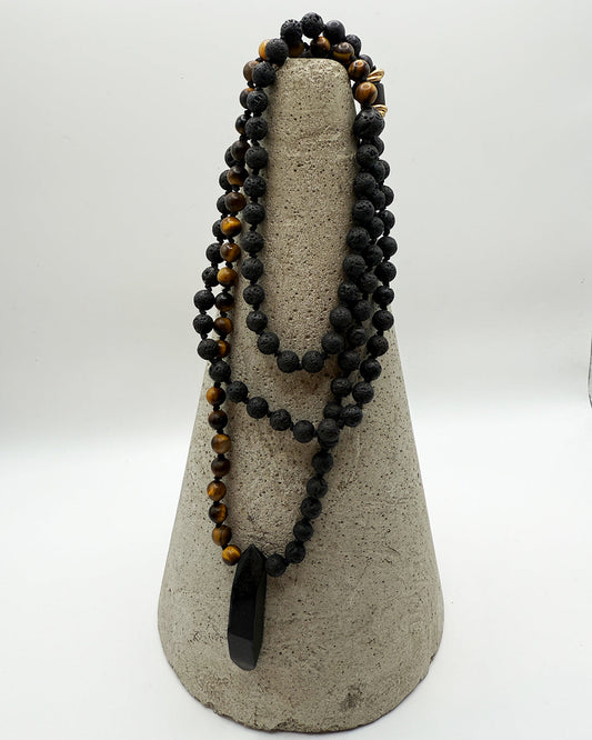 Black beaded necklace with a large pendant on a gray stand against a white background