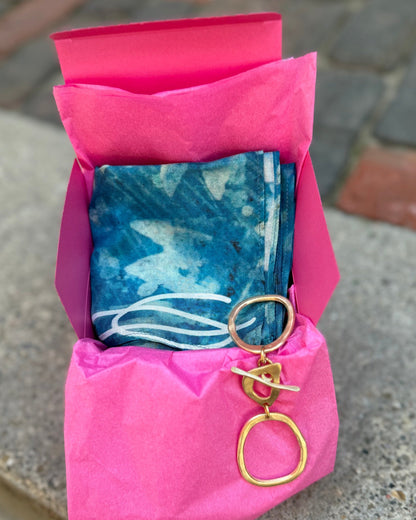 Pink pouch with blue fabric and gold keychain on a concrete surface